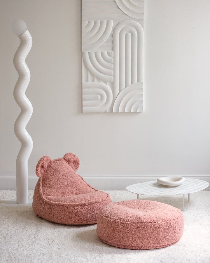 Blush pink Wigiwama bear chair and ottoman positioned against wavy sculptural wall panel