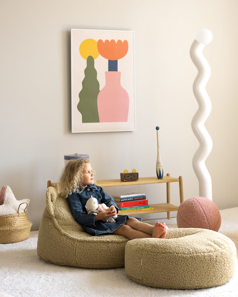 Child holding doll whilst sat in sage green Wigiwama bear chair, indoor lifestyle setting