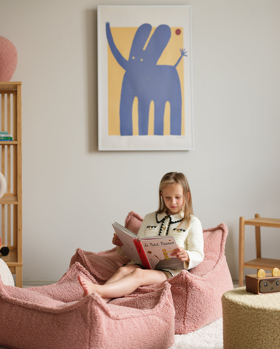 Child playing on beige Wigiwama beanbag with pink ottoman in furnished playroom