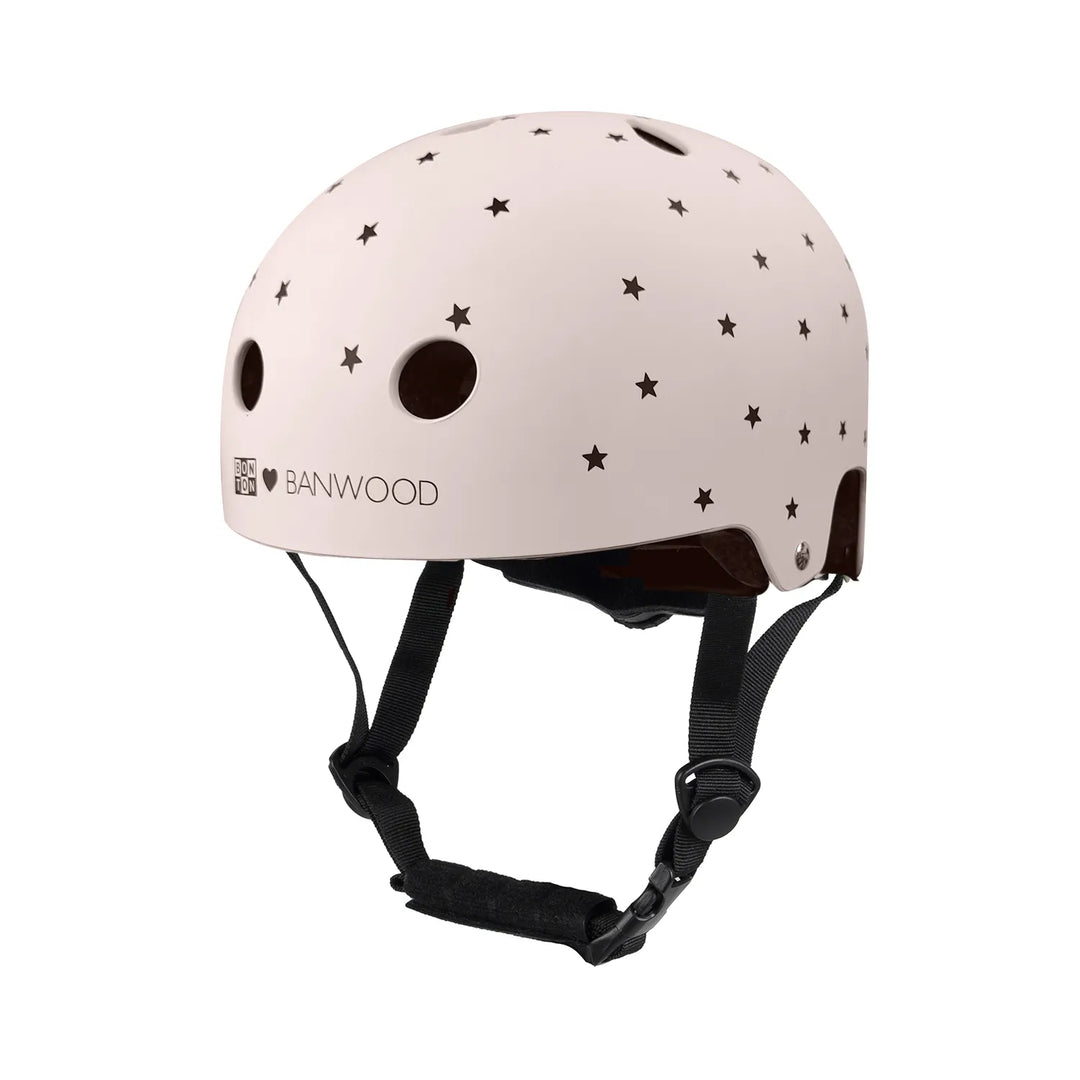 Matte pink Banwood helmet with black stars and ventilation holes, worn with black chin straps