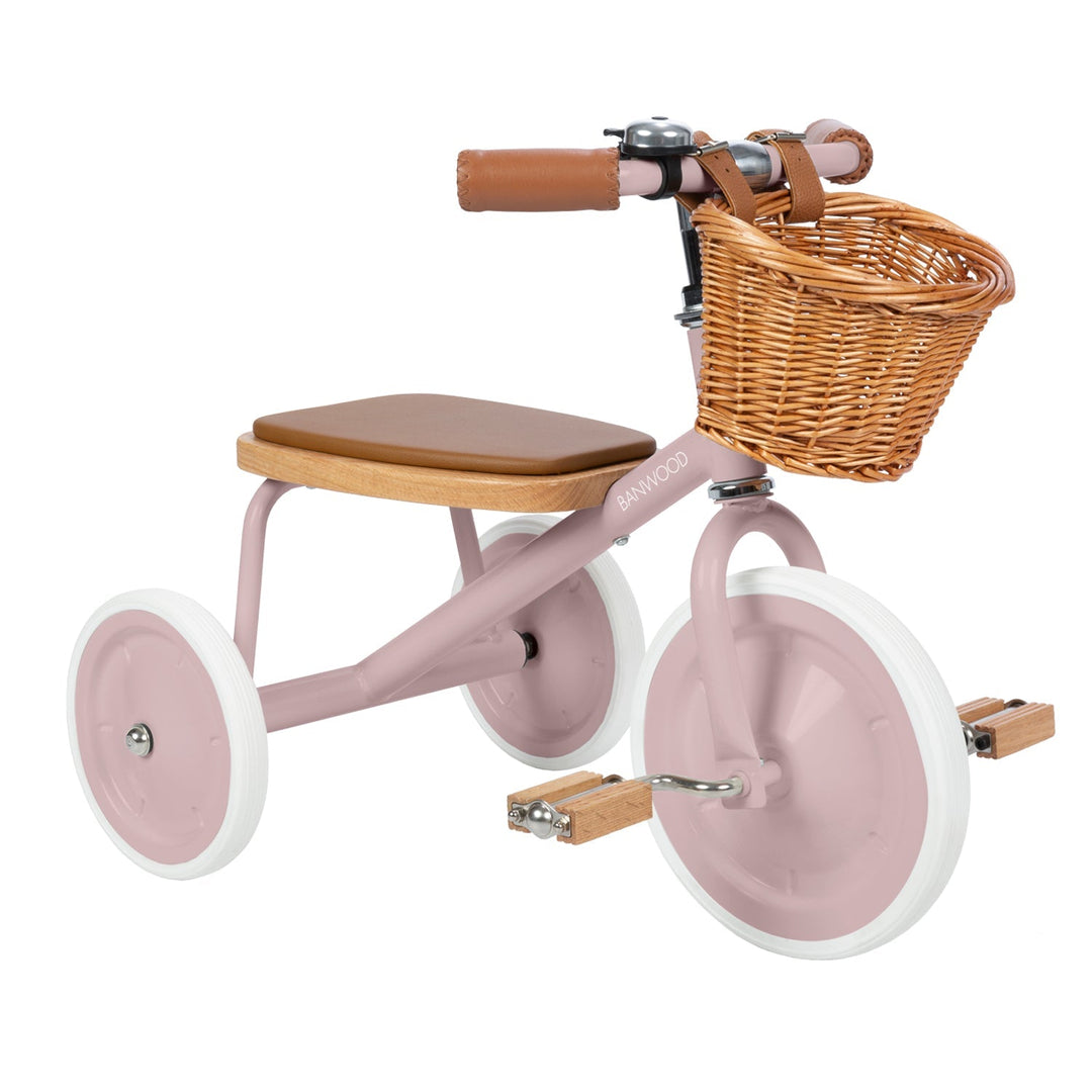Three-quarter view of dusty pink trike with padded oak seat and wooden pedals, Banwood