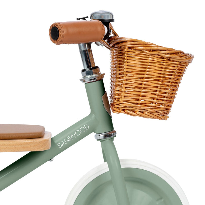 Close-up of handlebar with brown leather grip, safety bell and wicker basket detail