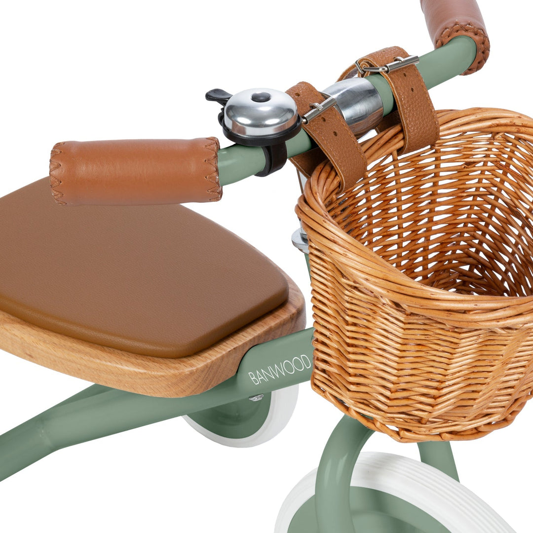 Handlebar detail showing vegan leather grip, safety bell and wicker basket texture