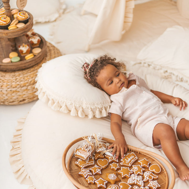 A baby resting on the MINICAMP Round Tassel Cushion