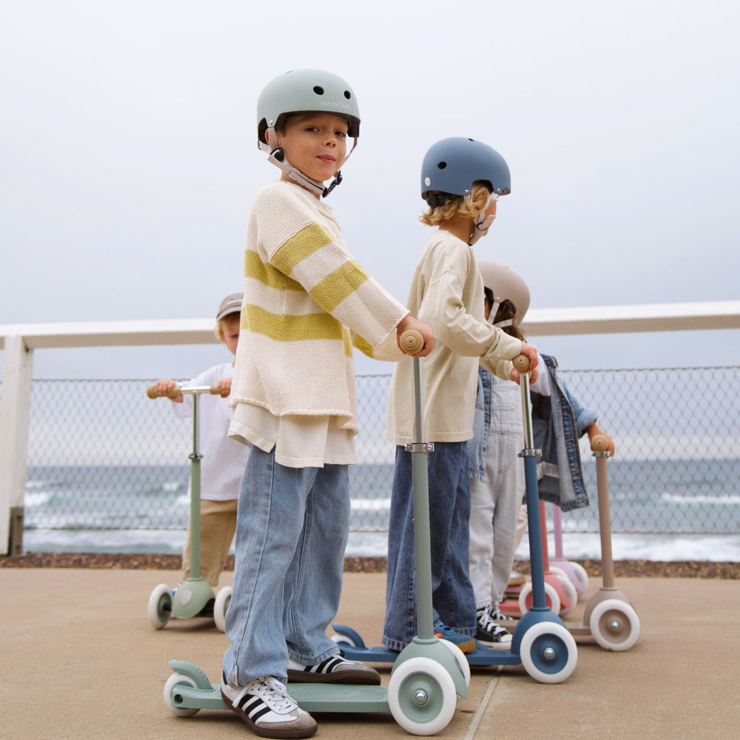 Group of children wearing various Banwood helmets with scooters at outdoor play area