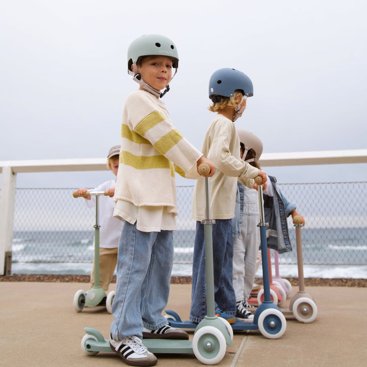Group of children wearing various Banwood helmets with scooters at outdoor play area