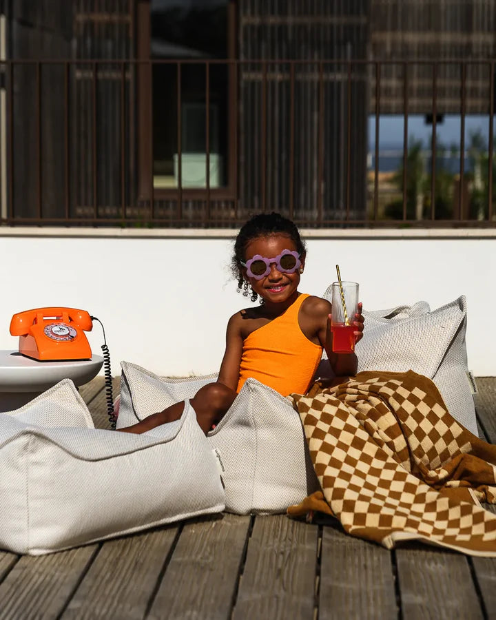 Two children in cream beanbag chairs on pool deck with modern architectural setting