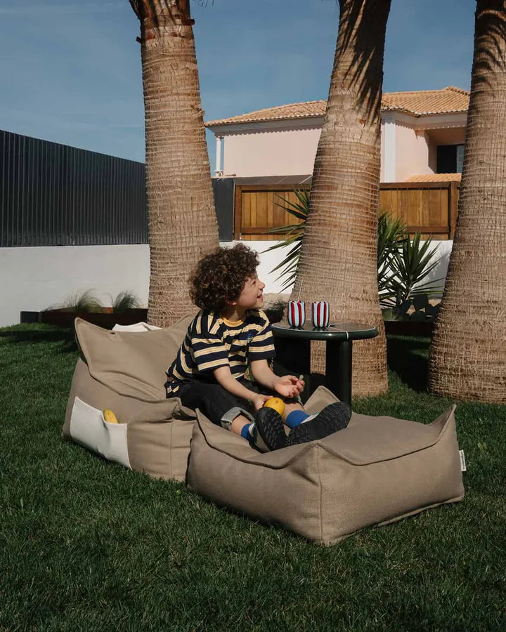 Beige bean bag chair in modern garden courtyard, seated child view