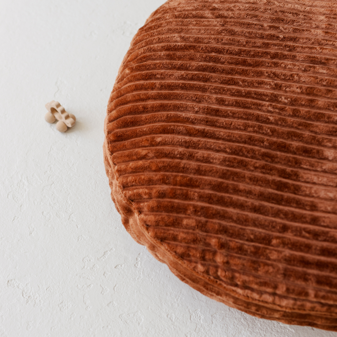 Close-up of the wide wale ribbed texture on the MINICAMP terracotta corduroy floor cushion
