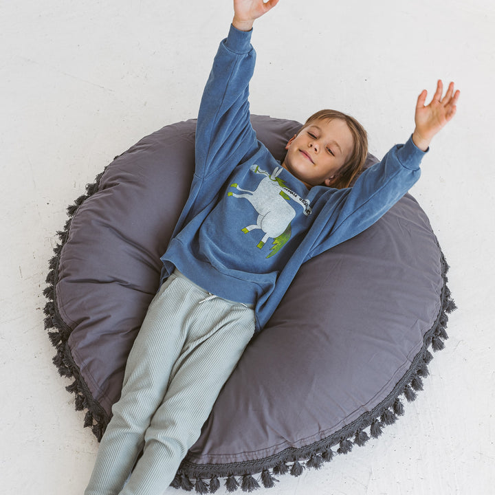 Child balancing on one foot on the MINICAMP grey floor cushion