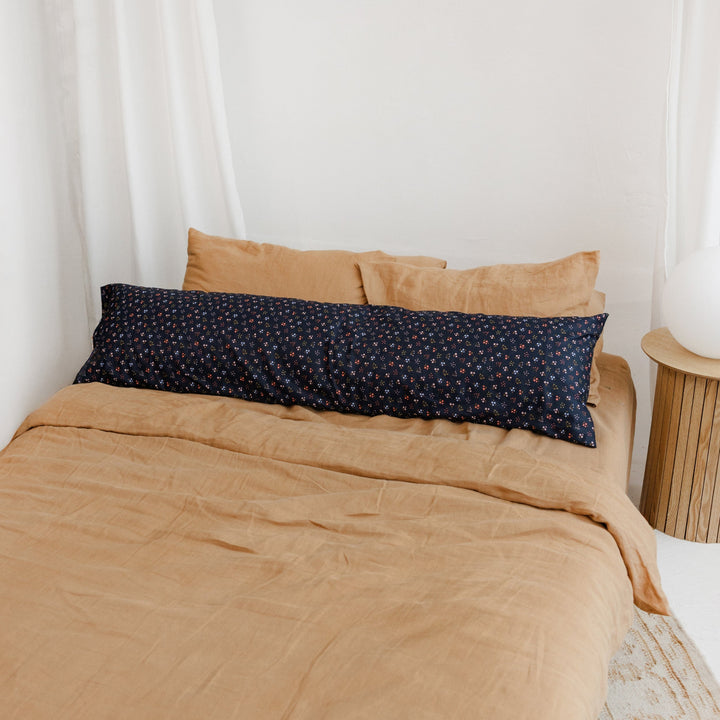 MINICAMP Long Maternity and Lumbar Support Pillow, navy blue floral organic cotton cover, styled on a bed