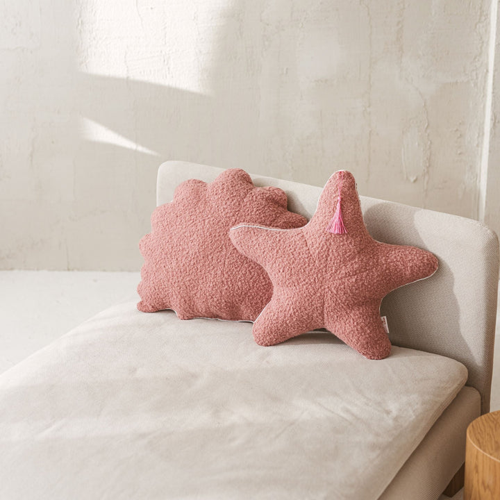 Rose bouclé seashell and starfish cushions styled together on a sofa
