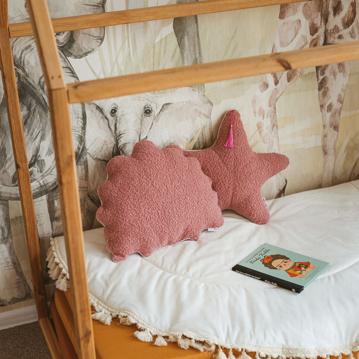 Rose bouclé starfish and seashell cushions styled together on a bed