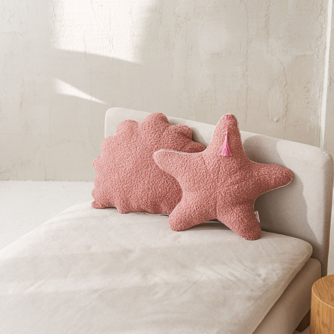 Rose bouclé starfish and seashell cushions styled together on a sofa