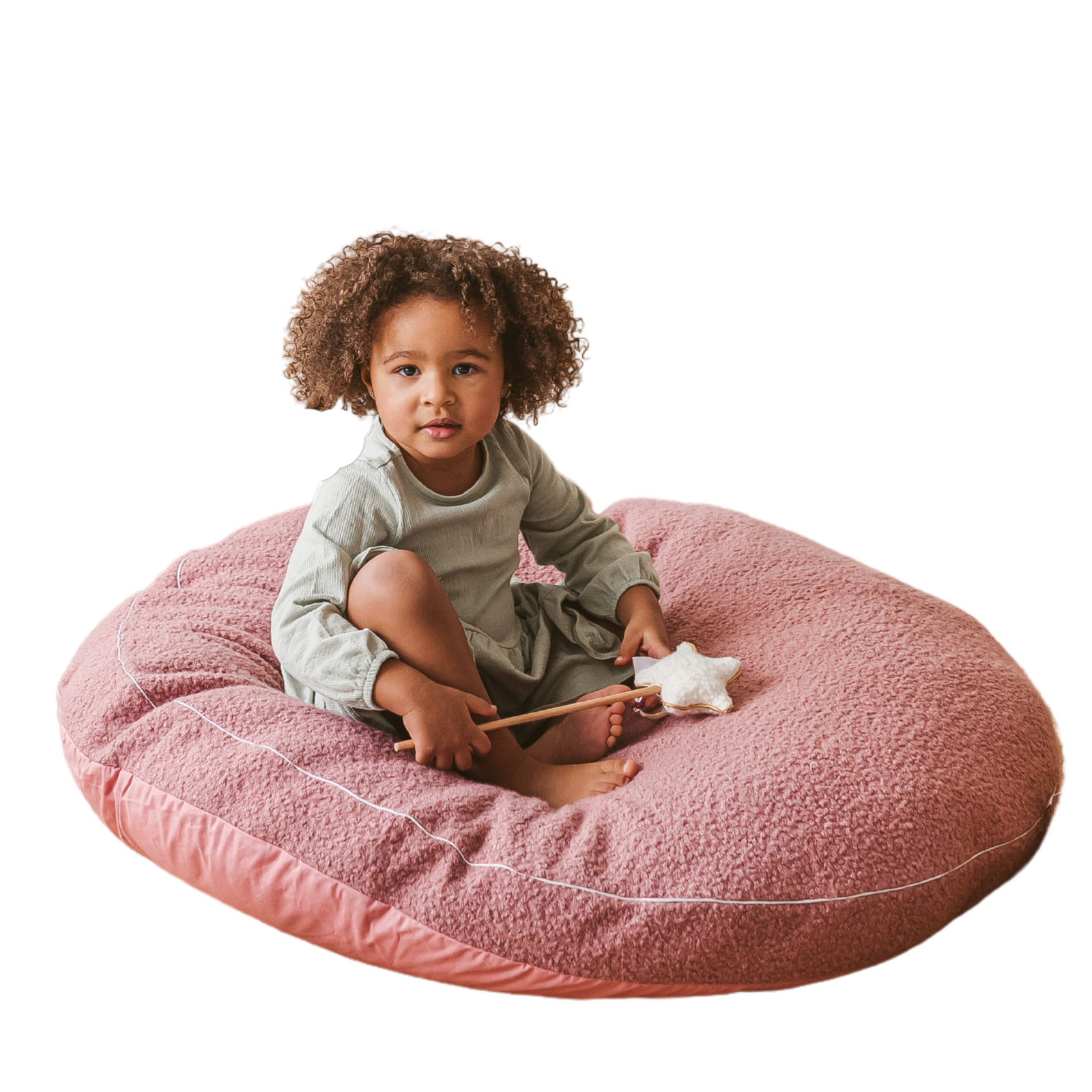 Child sitting on the MINICAMP round bouclé floor cushion in rose, holding a star-shaped wand toy