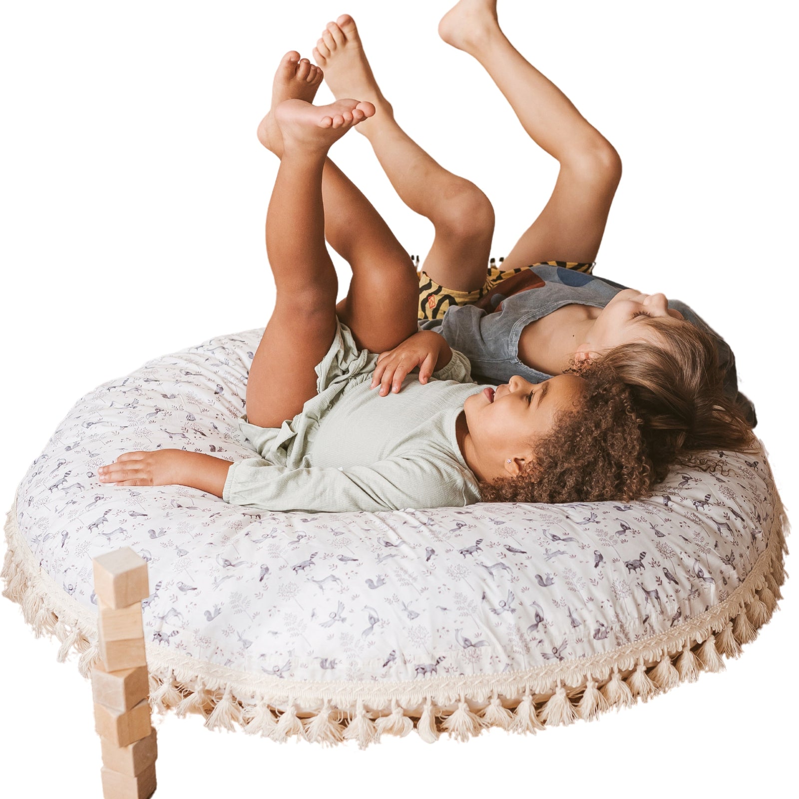 Two children lying on the MINICAMP forest animal print floor cushion with legs in the air, playful pose