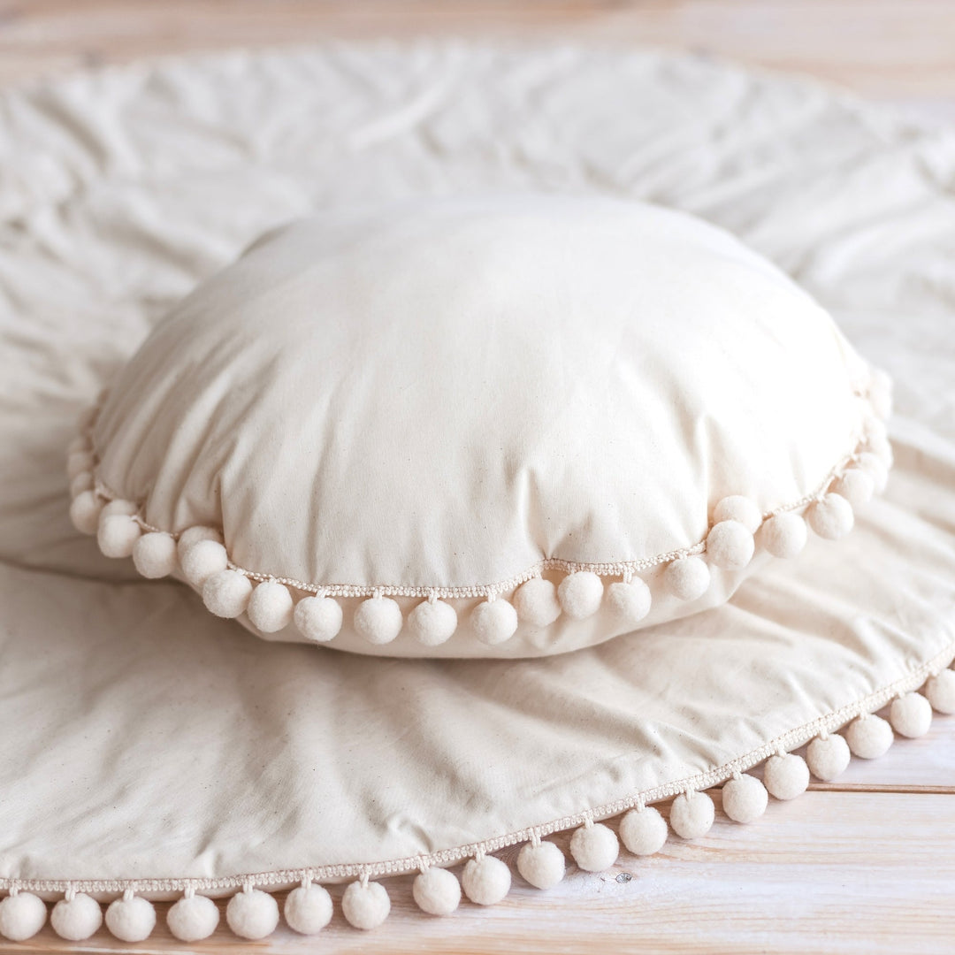 Close-up of the pompom trim on the MINICAMP Throw Pillow in Ecru