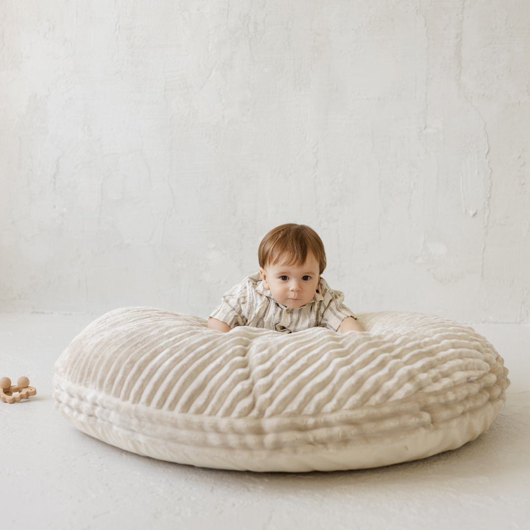 Baby leaning forward on the MINICAMP ecru corduroy floor cushion