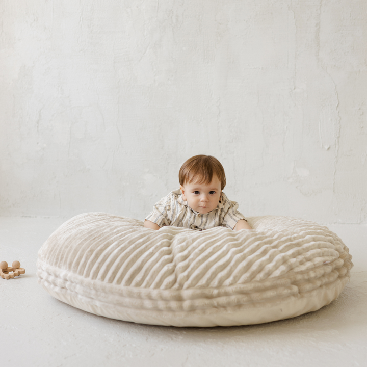 Baby leaning forward on the MINICAMP ecru corduroy floor cushion
