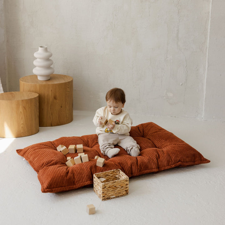 MINICAMP terracotta tufted floor cushion shown from a different angle