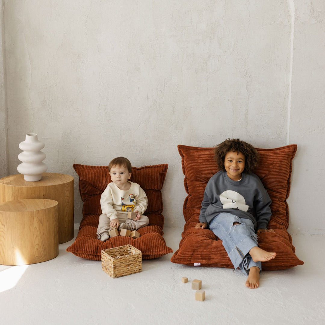 Baby playing with wooden blocks on the MINICAMP terracotta floor cushion
