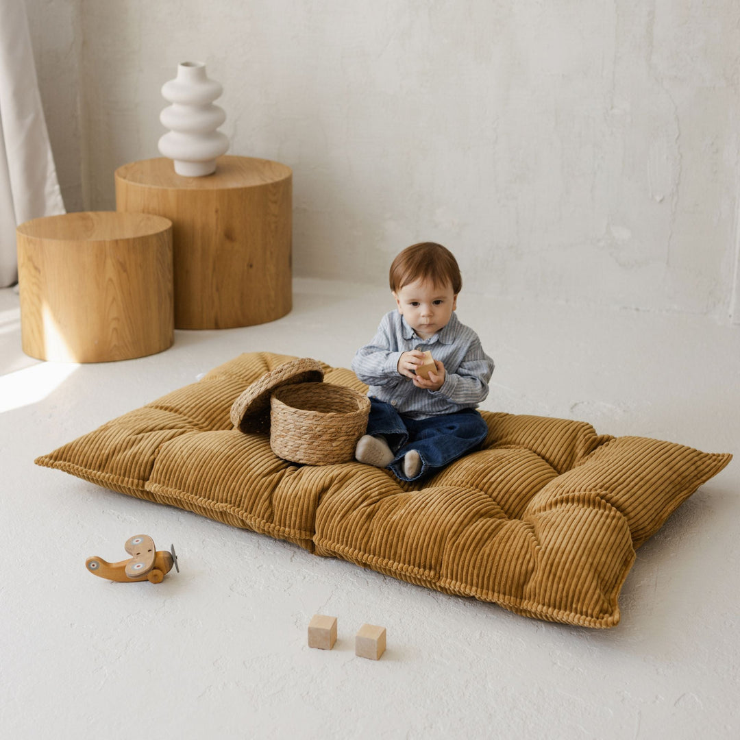Baby sitting with a woven basket on the MINICAMP mustard floor cushion
