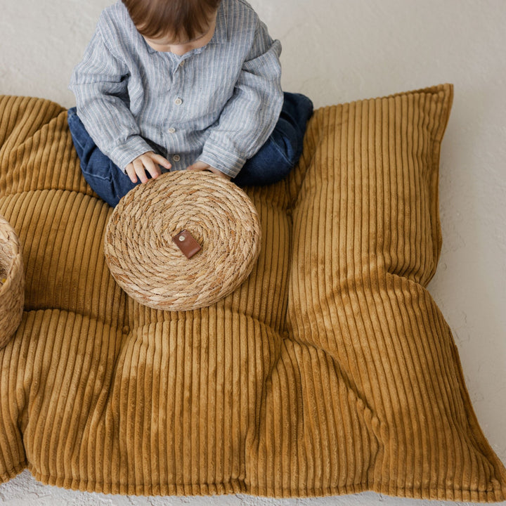 MINICAMP mustard tufted floor cushion shown from a different angle