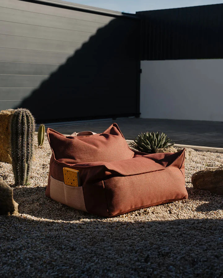 Burgundy bean bag chair outdoors in desert garden setting