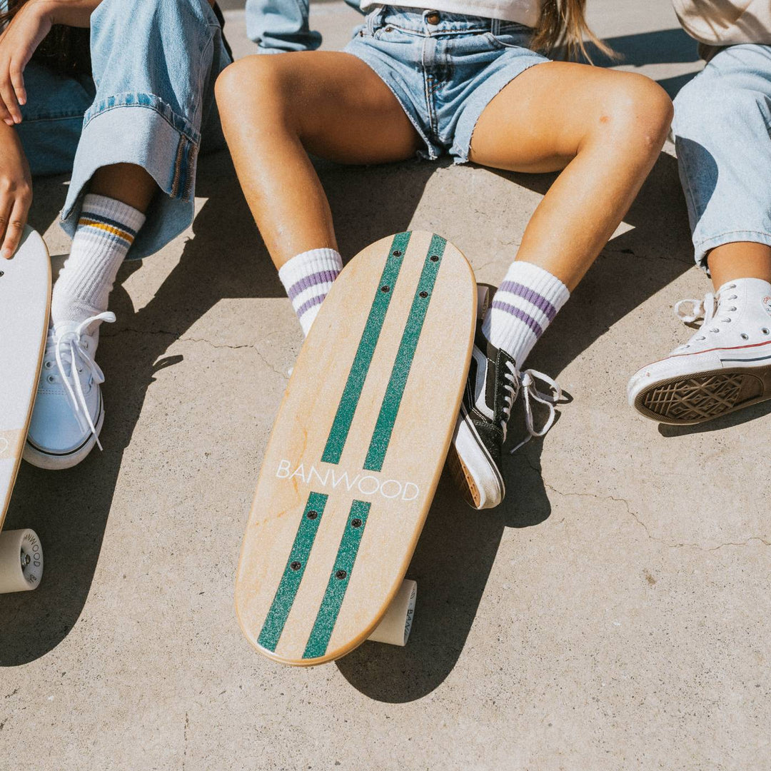 Three-quarter angle of Banwood skateboard with cream wheels on white surface