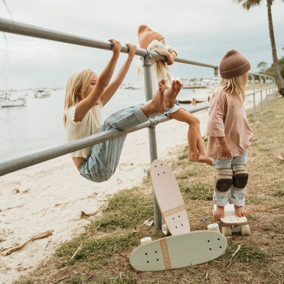 Children with mint skateboards at seaside location near metal railings