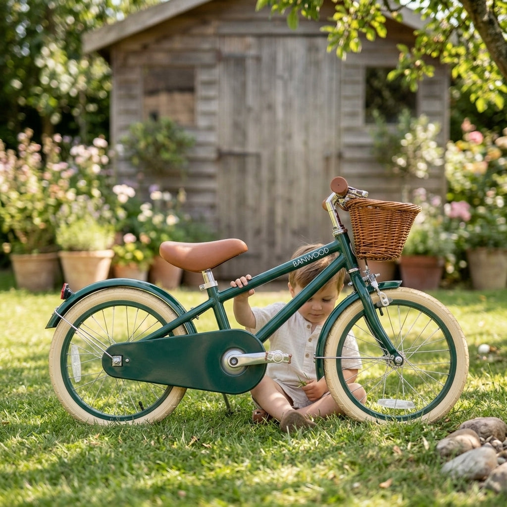 Child beside the green Banwood Classic Bicycle on a garden lawn
