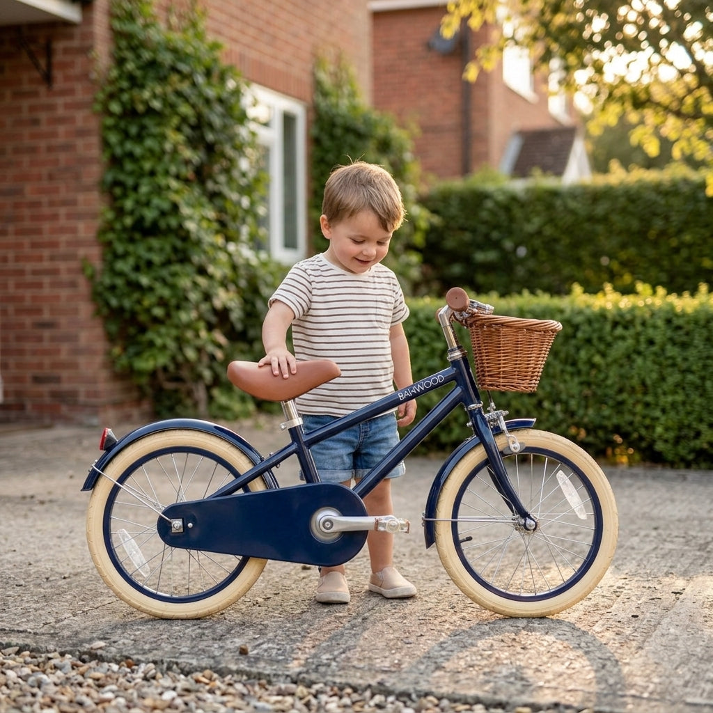 Child standing beside the navy Banwood Classic Bicycle on a home driveway