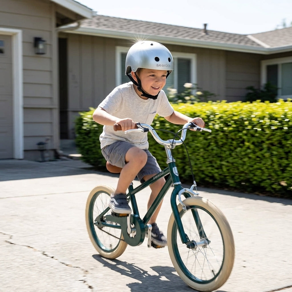 Child riding a bicycle outdoors wearing the Banwood Classic Helmet in chrome