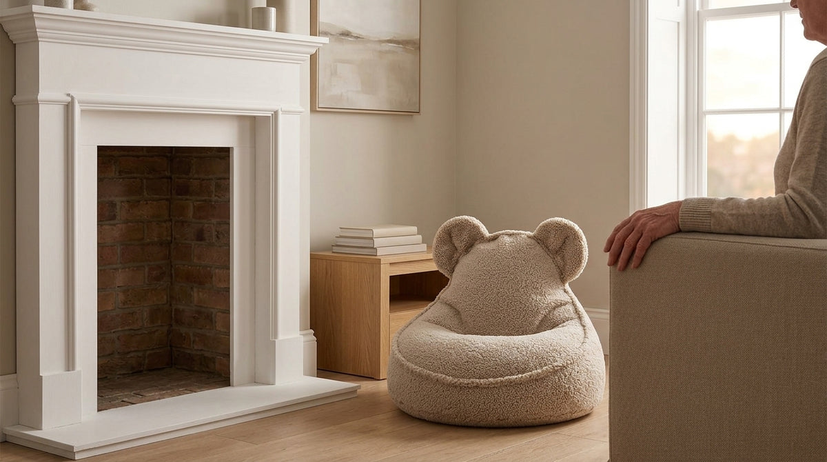 Wigiwama Bear Beanbag in biscuit teddy fabric beside a fireplace in a family sitting room