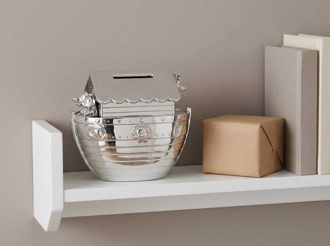 Personalised Silver Noah's Ark Money Box on a nursery shelf next to a small wrapped gift
