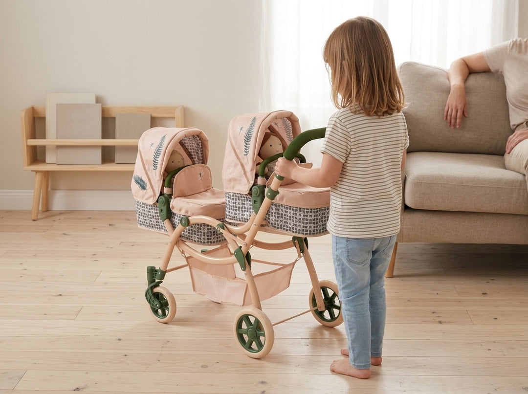 Child with the Roma RHS Twin Dolls Pram in Fern and two dolls in a playroom, an adult on the sofa nearby