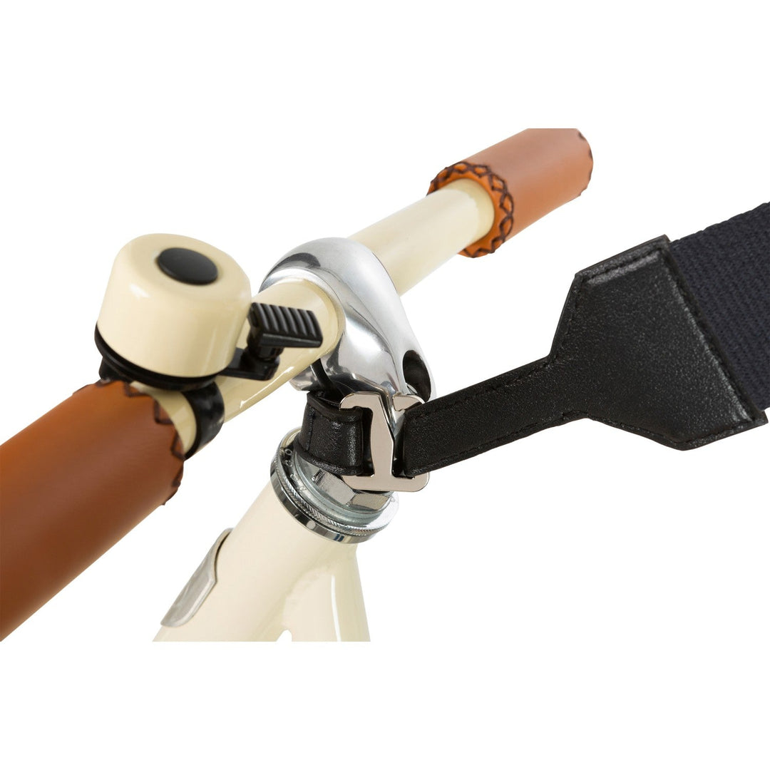 Cream balance bike handlebar with black carry strap and wooden grip detail