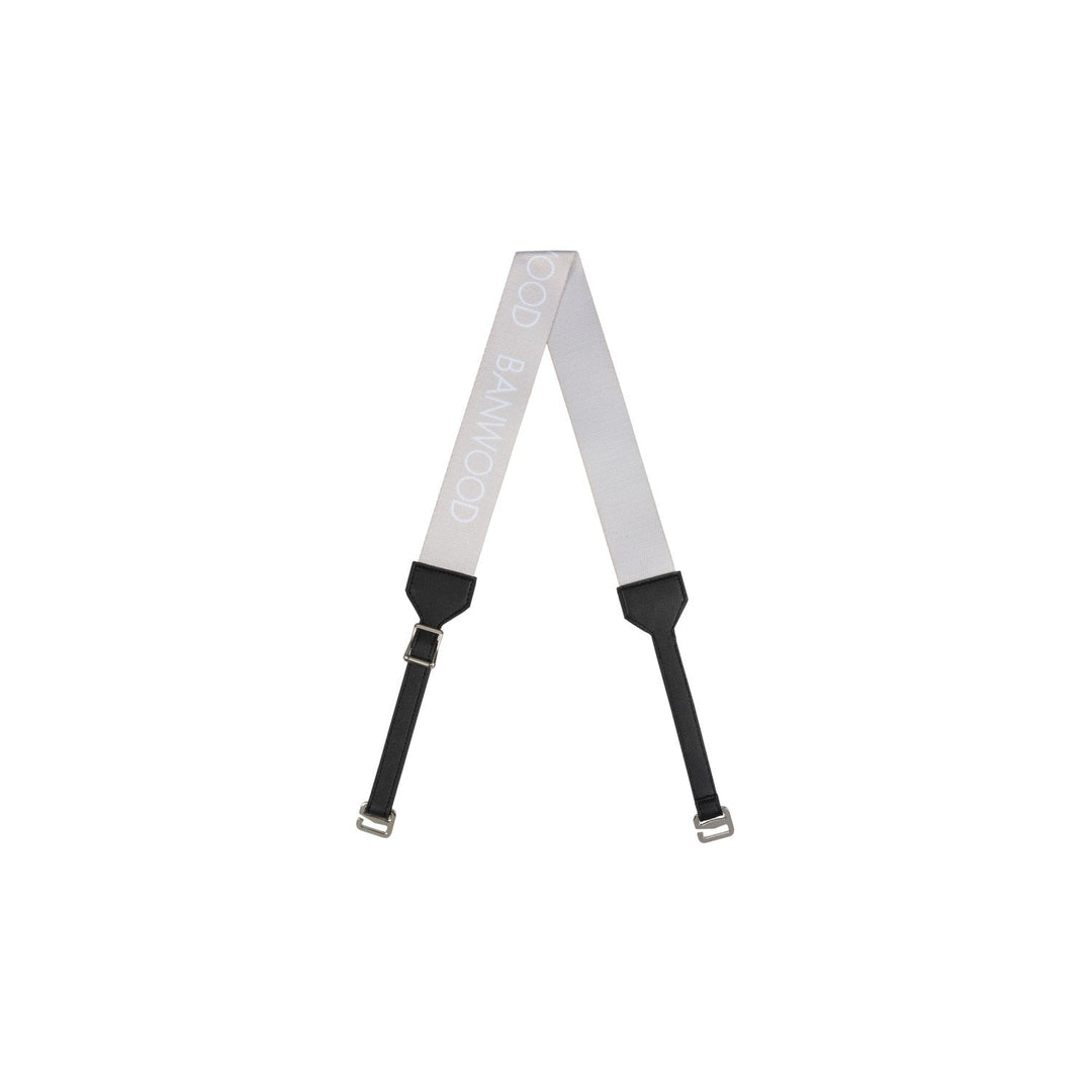 Cream carry strap with black padded sections and metal buckles laid flat in A-shape