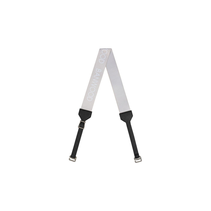 Cream carry strap with black padded sections and metal buckles laid flat in A-shape