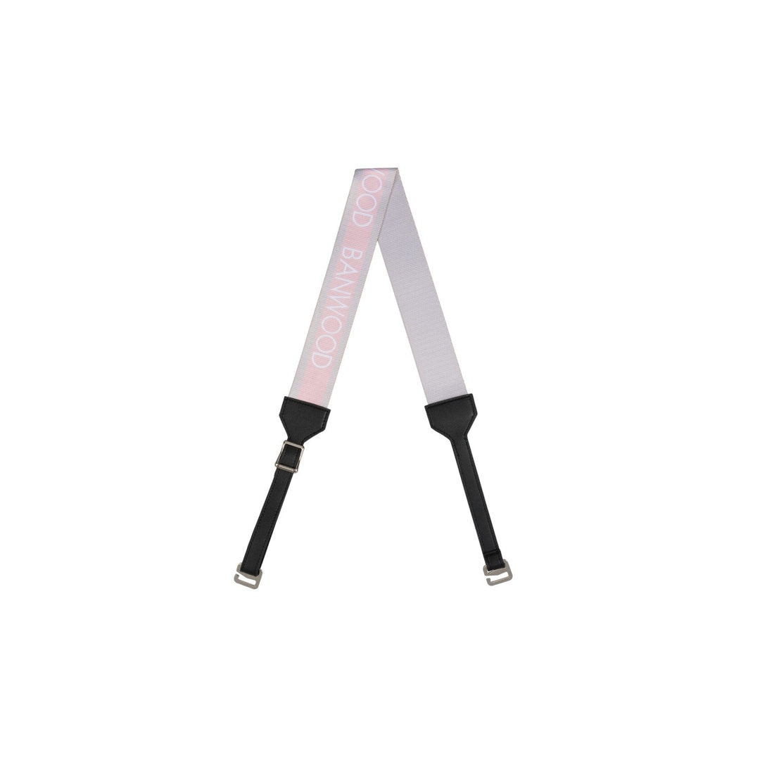 Pink striped carry strap with black pads and metal buckles, flat lay