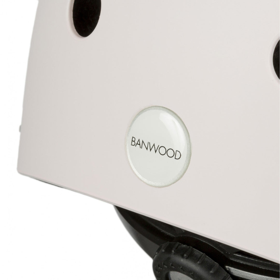 Close-up of pale pink helmet side showing Banwood badge and black ventilation hole detail