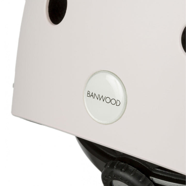 Close-up of pale pink helmet side showing Banwood badge and black ventilation hole detail