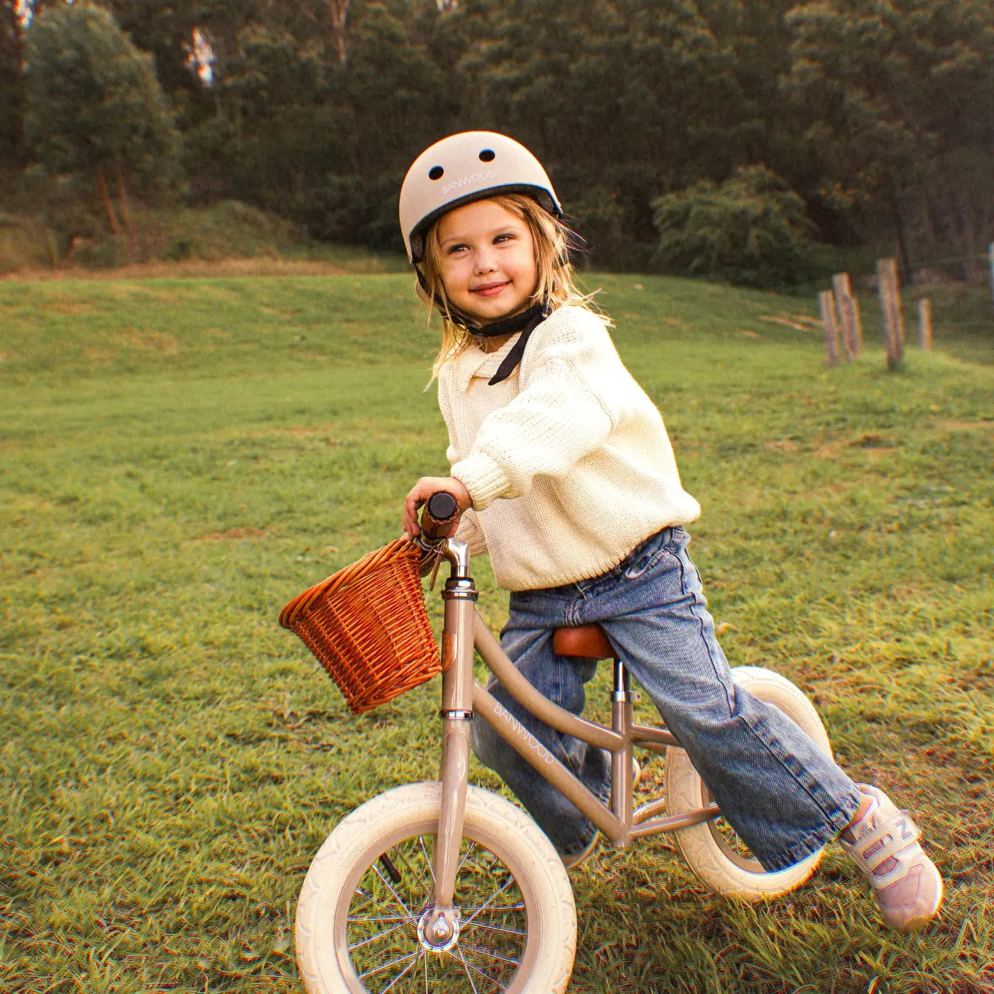Child on bicycle wearing beige safety helmet outdoors Banwood