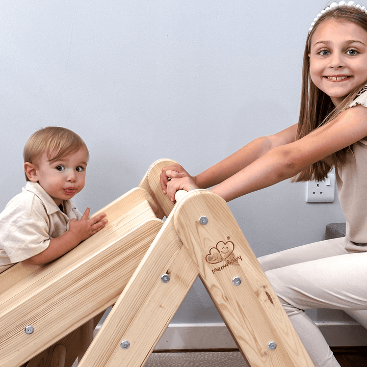 Toddler and older girl resting their hands on the slide and top rung of a natural solid wood MeowBaby climbing set