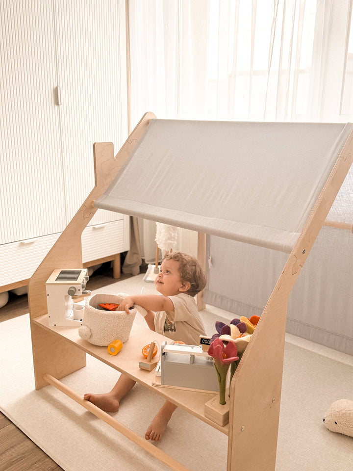 Child playing with a wooden toy kitchen set on the bench inside the MeowBaby Wooden Playhouse