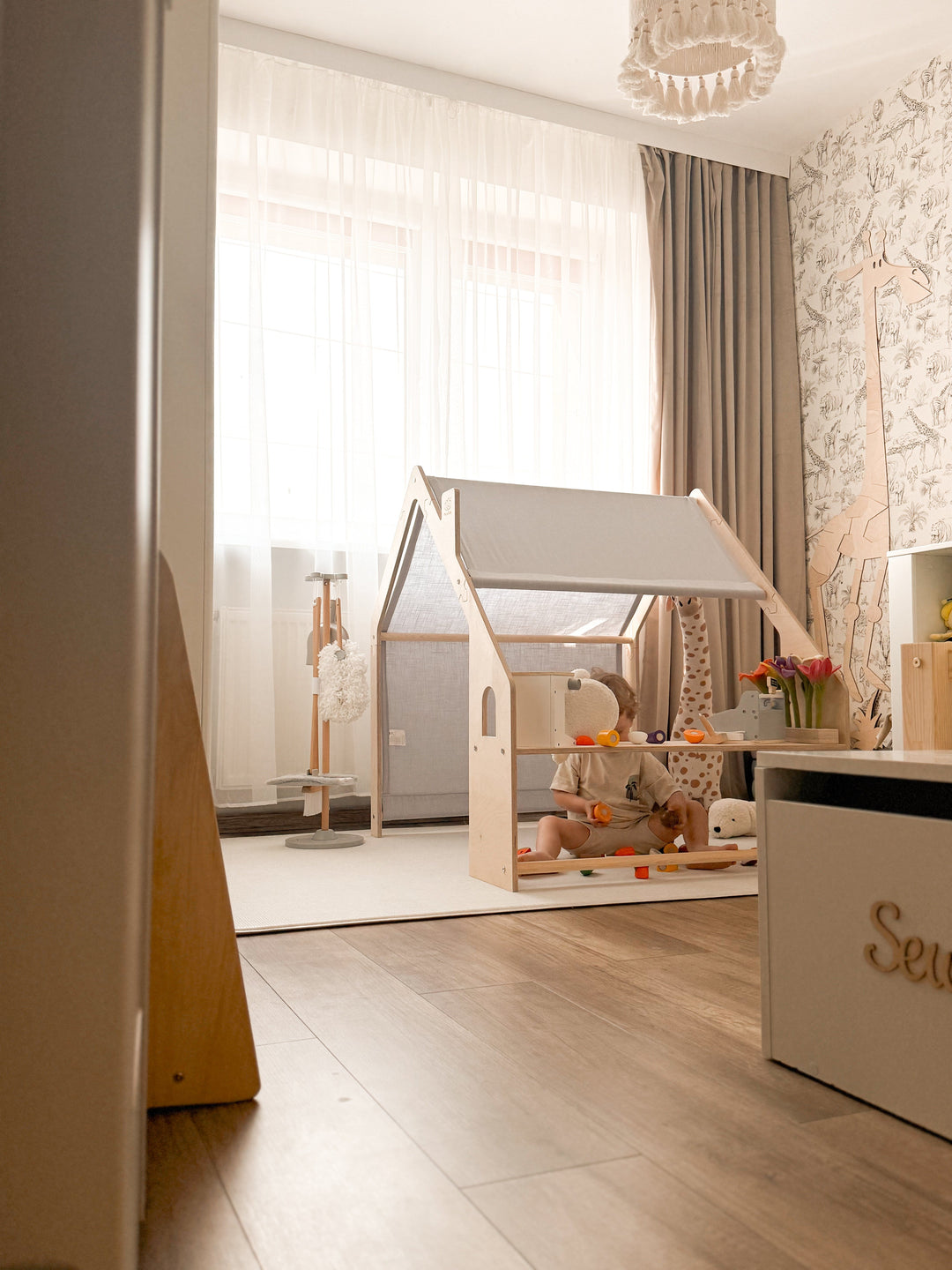 Wide view of the MeowBaby Wooden Playhouse set up in a safari-themed nursery, with a child playing on the bench