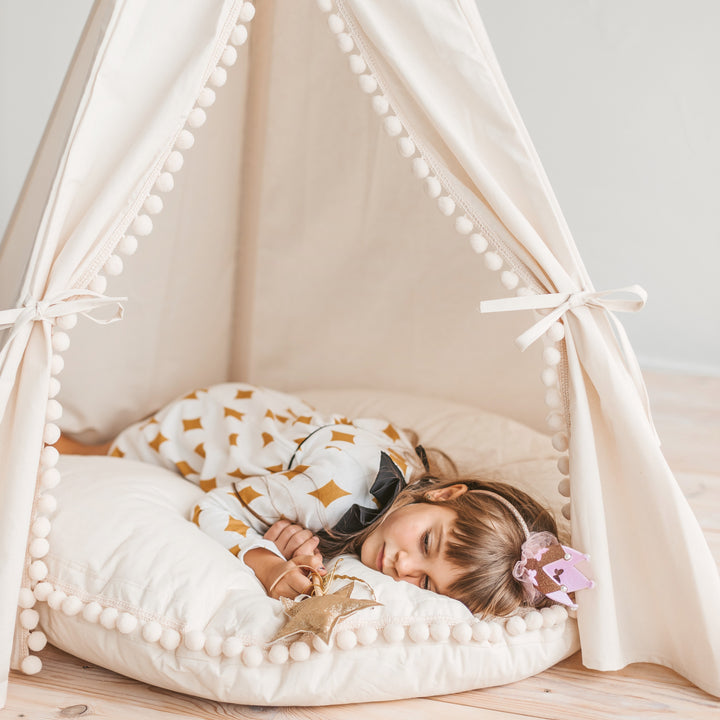 MINICAMP ecru pom pom floor cushion, angled view