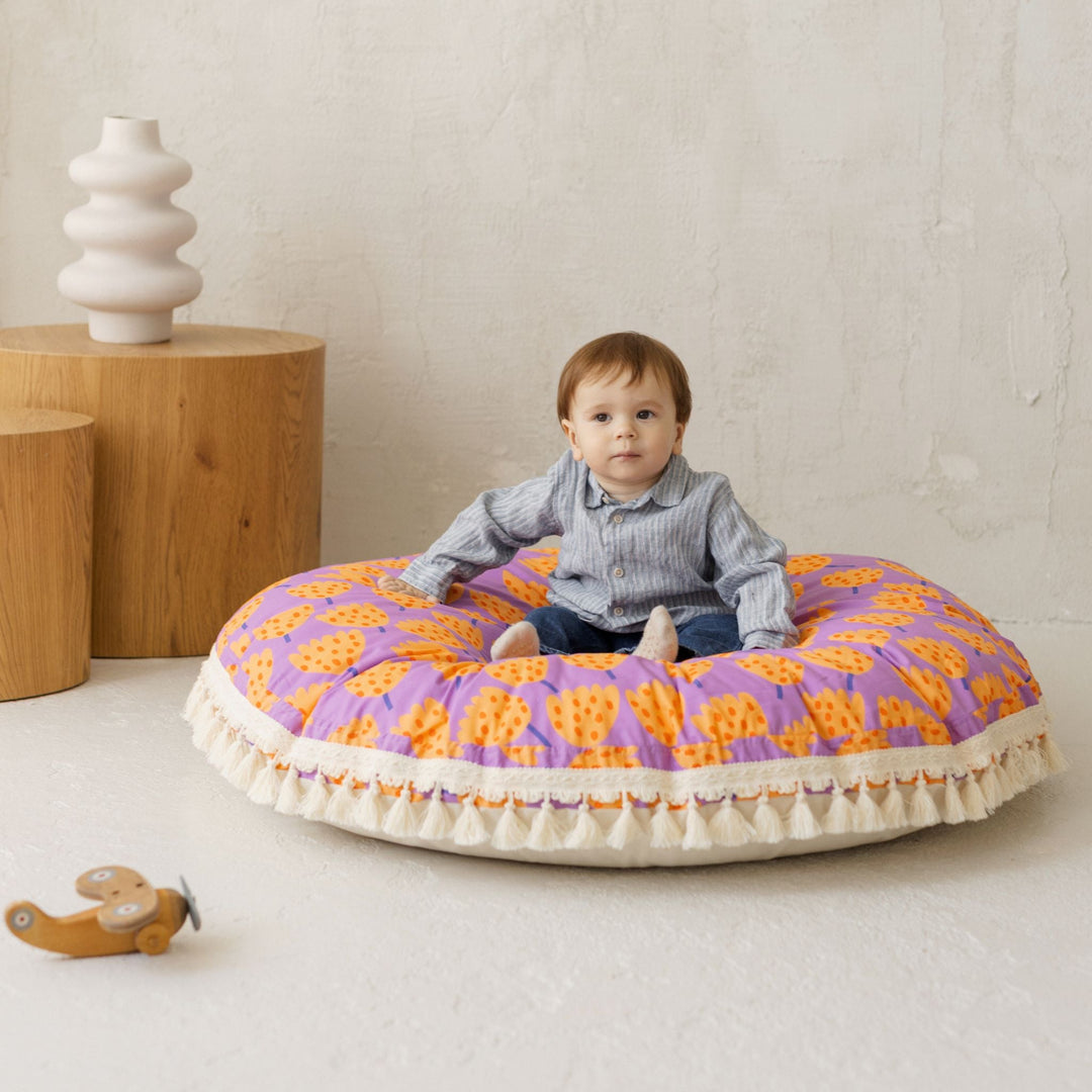 Baby sitting on the MINICAMP large floor cushion in vibrant tulip pattern