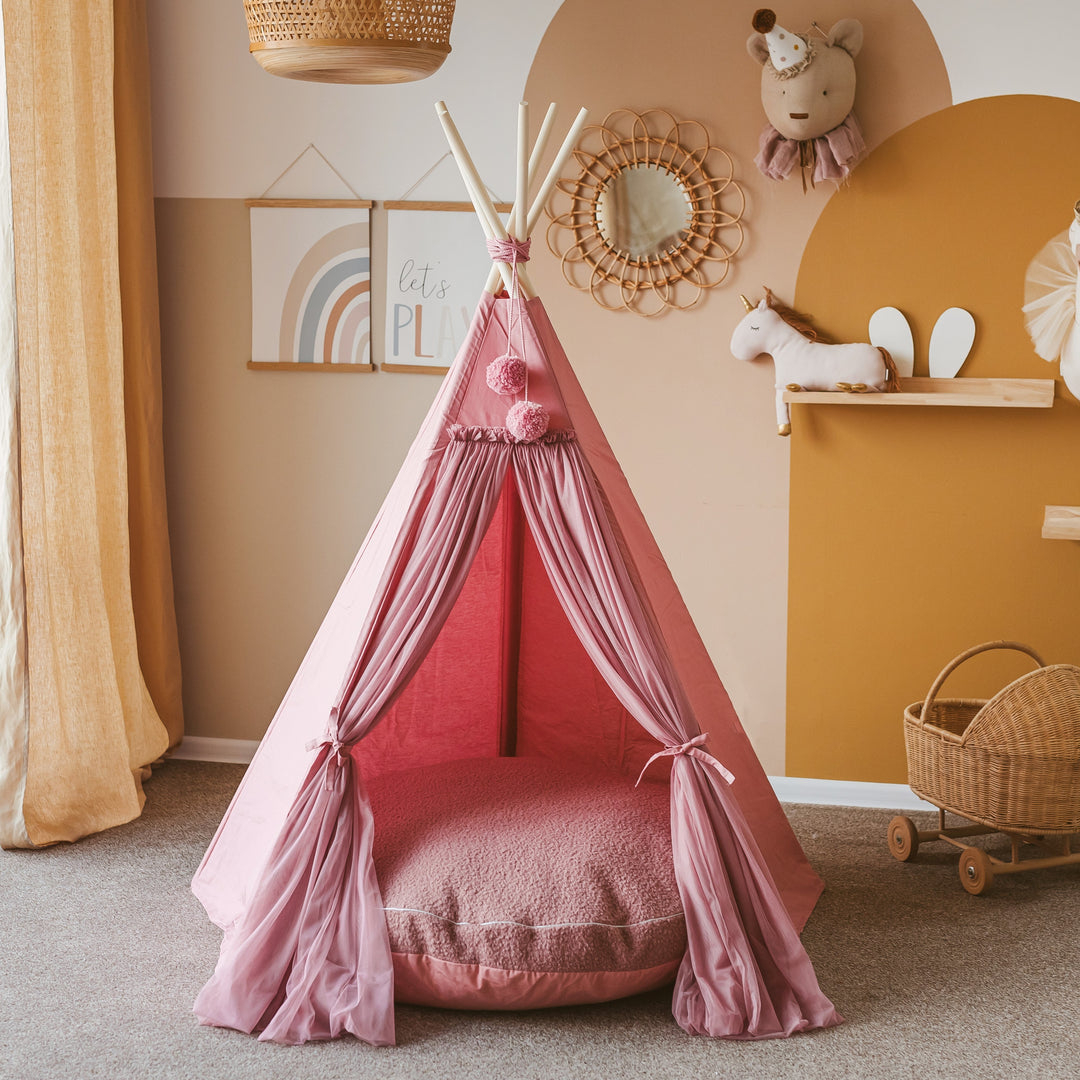 The MINICAMP rose bouclé floor cushion styled inside a pink play teepee as a reading nook