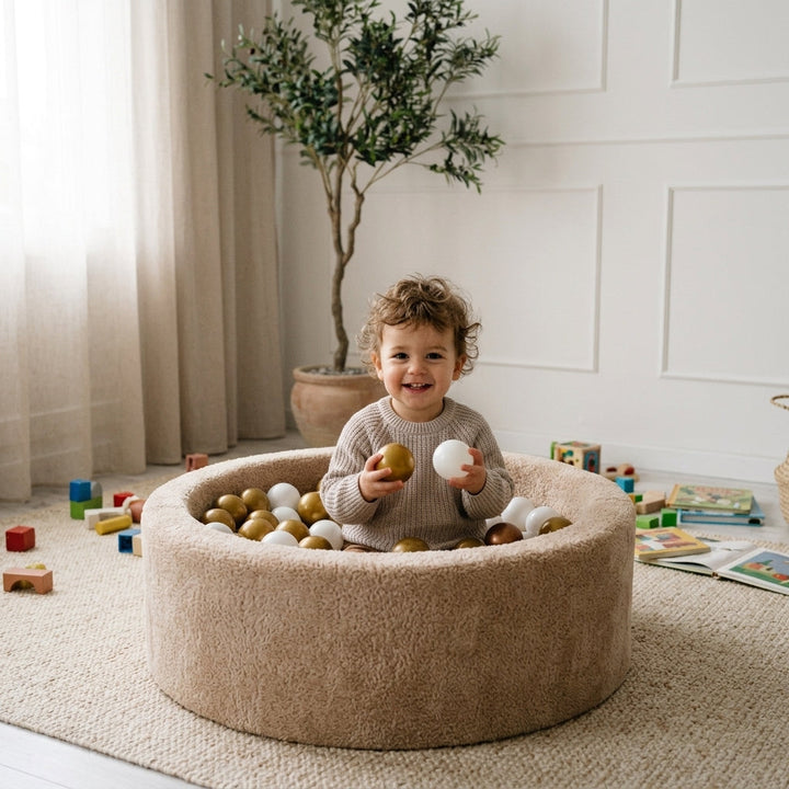 Toddler playing inside the Monio for Kids Beige Plush Round Ball Pit at home